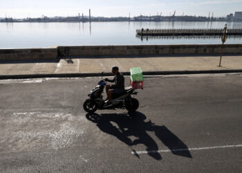 Una persona en motocicleta por el malecón. Foto: Ernesto Mastrascusa/EFE.