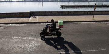 Una persona en motocicleta por el malecón. Foto: Ernesto Mastrascusa/EFE.