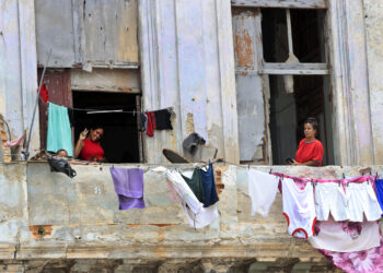 Personas saludan desde un balcón, en La Habana. Foto: Ernesto Mastrascusa/EFE.