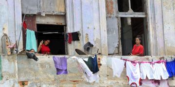 Personas saludan desde un balcón, en La Habana. Foto:  Ernesto Mastrascusa/EFE.