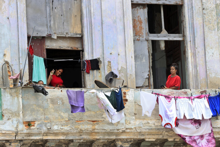 Personas saludan desde un balcón, en La Habana. Foto:  Ernesto Mastrascusa/EFE.