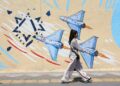 Una joven iraní pasa junto a un mural antiisraelí en una calle de Teherán, Irán. Foto: ABEDIN TAHERKENAREH / EFE/ EPA.