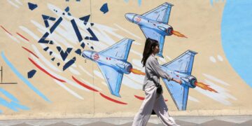 Una joven iraní pasa junto a un mural antiisraelí en una calle de Teherán, Irán. Foto: ABEDIN TAHERKENAREH / EFE/ EPA.