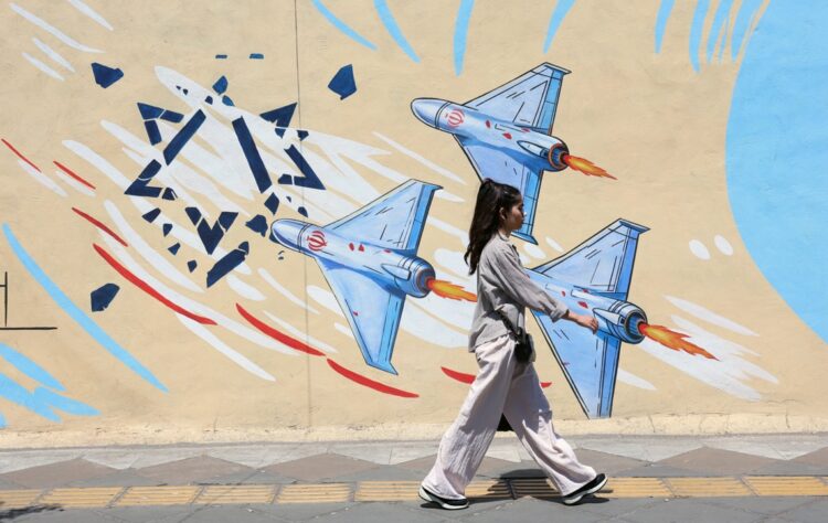 Una joven iraní pasa junto a un mural antiisraelí en una calle de Teherán, Irán. Foto: ABEDIN TAHERKENAREH / EFE/ EPA.