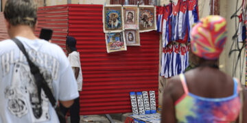 Personas caminando junto a un lugar de venta de artesanías en La Habana. Foto: Ernesto Mastrascusa/ EFE.