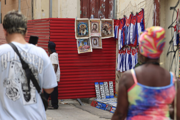 Personas caminando junto a un lugar de venta de artesanías en La Habana. Foto: Ernesto Mastrascusa/ EFE.