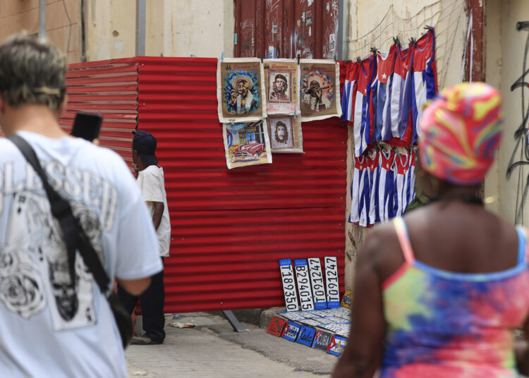Personas caminando junto a un lugar de venta de artesanías en La Habana. Foto: Ernesto Mastrascusa/ EFE.