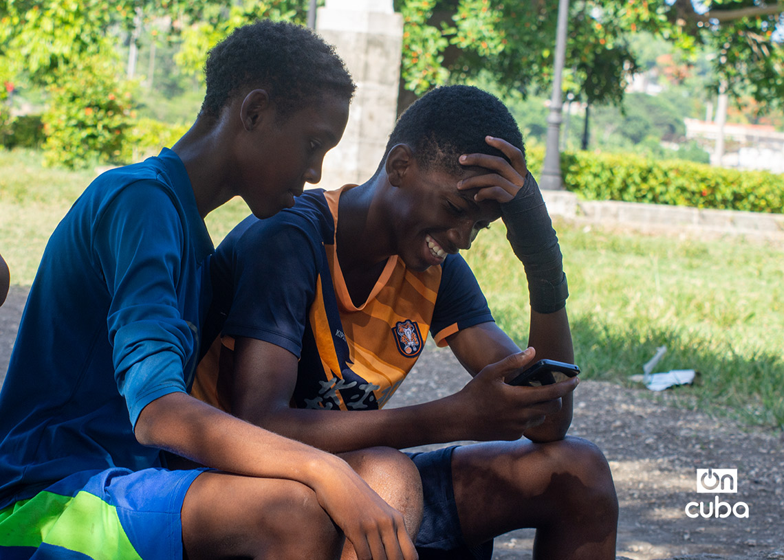Niños revisan un celular mientras esperan para jugar fútbol en La Habana durante la Copa Mundial de 2026. Foto: Otmaro Rodríguez.