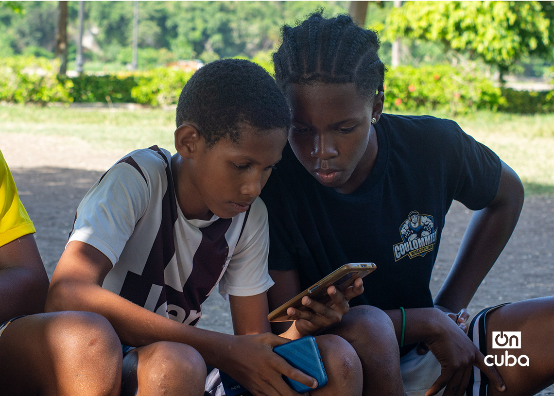 Niños revisan un celular mientras esperan para jugar fútbol en La Habana durante la Copa Mundial de 2026. Foto: Otmaro Rodríguez.