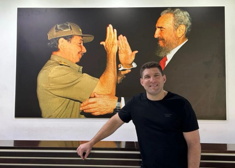 Raúl Guillermo Rodríguez Castro posa frente a una foto de Fidel Castro y Raúl Castro. Foto: Romina Ruiz-Goiriena, USA TODAY.