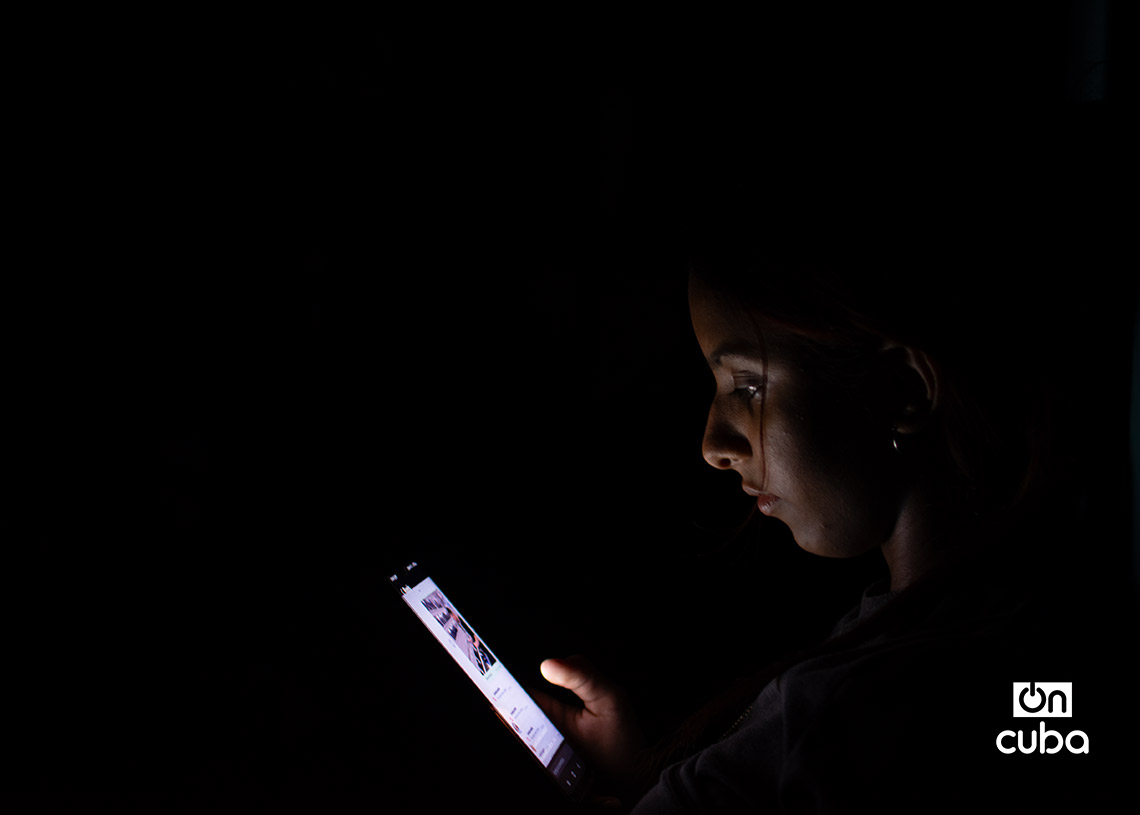 Una joven revisa su teléfono celular durante un apagón en la Habana Vieja. Foto: Otmaro Rodríguez.