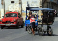 Un hombre vestido con una camiseta de la bandera de EE.UU., empuja un bicitaxi en La Habana. Foto: Ernesto Mastrascusa / EFE.
