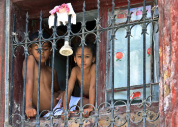 Niños mirando desde una ventana en La Habana. Foto: Ernesto Mastrascusa/EFE.