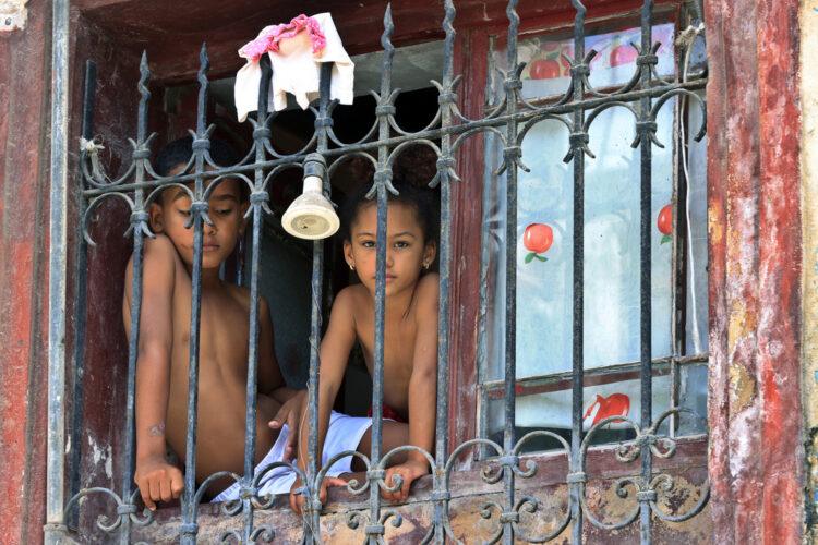 Niños mirando desde una ventana en La Habana. Foto: Ernesto Mastrascusa/EFE.
