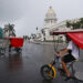 Personas pasan en bicitaxis frente al Capitolio de La Habana. Foto: Ernesto Mastrascusa/EFE.
