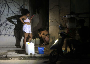 Dos mujeres llenan recipientes con agua durante un apagón en La Habana. Foto: Ernesto Mastrascusa / EFE.