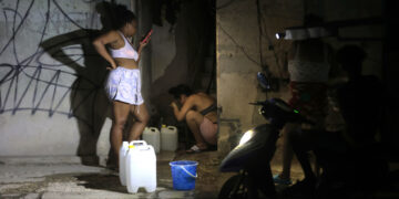 Dos mujeres llenan recipientes con agua durante un apagón en La Habana. Foto: Ernesto Mastrascusa / EFE.