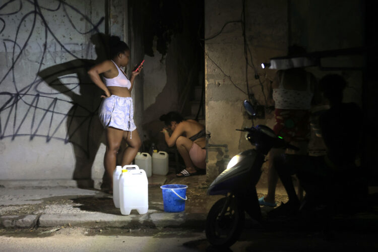 Dos mujeres llenan recipientes con agua durante un apagón en La Habana. Foto: Ernesto Mastrascusa / EFE.