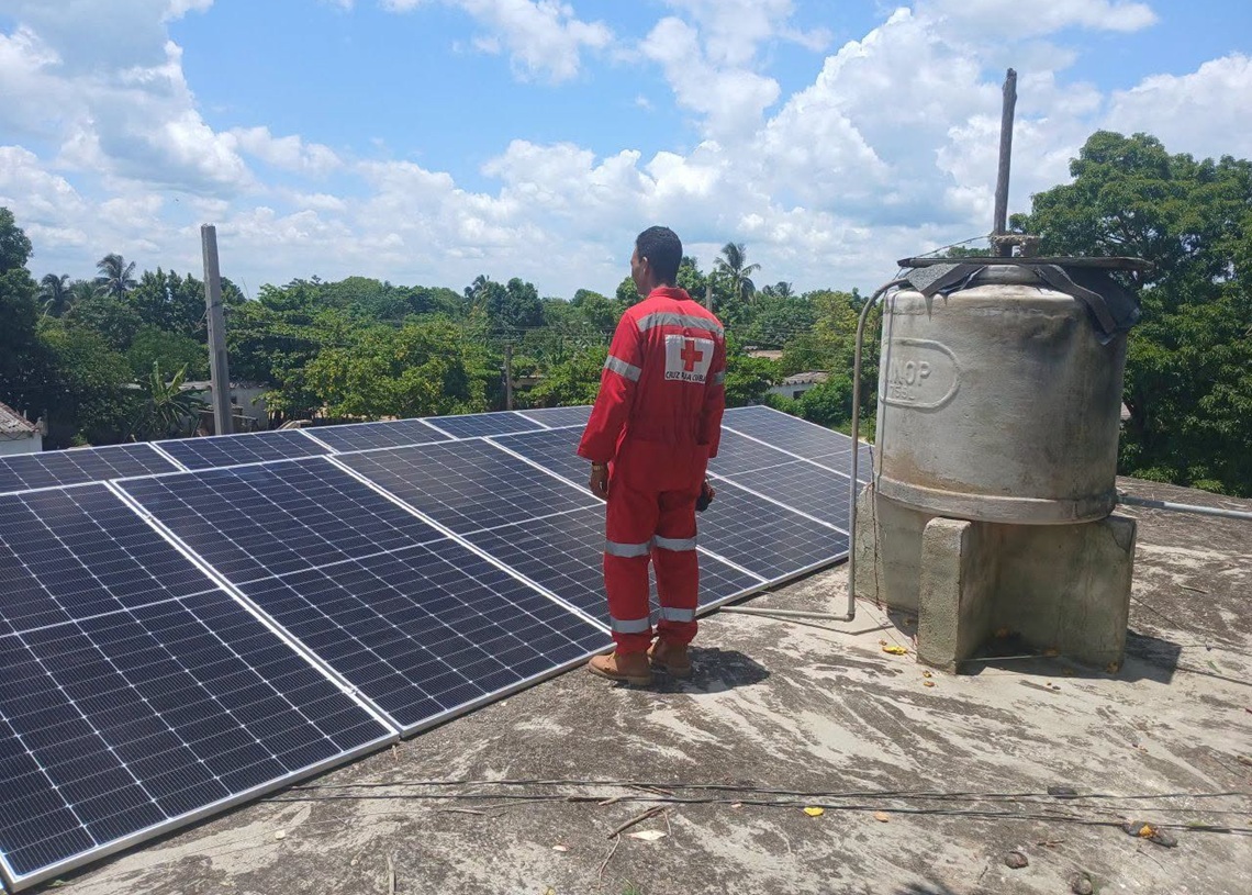 Un voluntario de la Cruz Roja junto a paneles solares instalados por esa entidad en un centro de salud de la provincia de Granma. Foto: Radio Ciudad Monumento / Facebook.