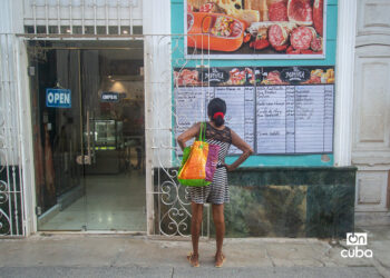 Una mujer lee la pizarra de precios de un negocio privado en La Habana. Foto: Otmaro Rodríguez.