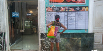 Una mujer lee la pizarra de precios de un negocio privado en La Habana. Foto: Otmaro Rodríguez.