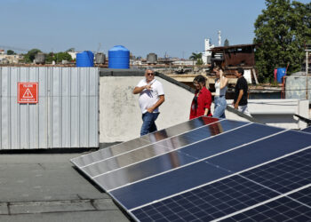 Presidente de JOLYNI S.U.R.L, Jorge Félix Peraza Noriega, caminando junto a paneles fotovoltaicos en La Habana. Foto:  Ernesto Mastrascusa/EFE.