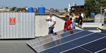 Presidente de JOLYNI S.U.R.L, Jorge Félix Peraza Noriega, caminando junto a paneles fotovoltaicos en La Habana. Foto:  Ernesto Mastrascusa/EFE.