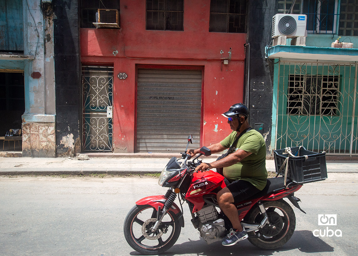 Un motociclista pasa frente a un negocio privado cerrado en La Habana. Foto: Otmaro Rodríguez.