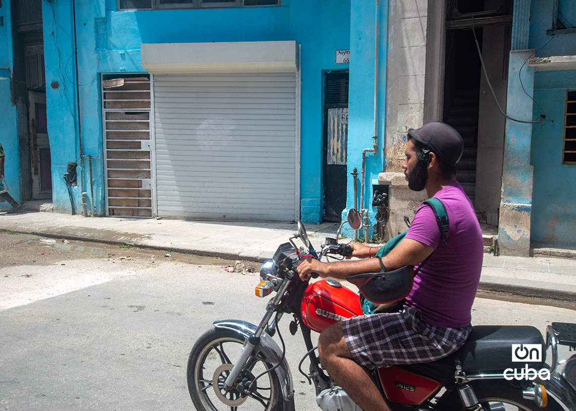 Un motociclista pasa frente a un negocio privado cerrado en La Habana. Foto: Otmaro Rodríguez.
