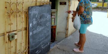 Una mujer observa la pizarra de precios en una bodeguita privada en La Habana, en agosto de 2026. Foto: AMD.