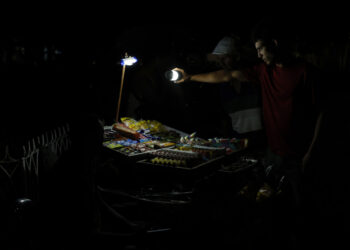 Una persona ilumina con una linterna para ver productos en un puesto callejero en La Habana (Cuba). Foto: EFE/ Ernesto Mastrascusa.
