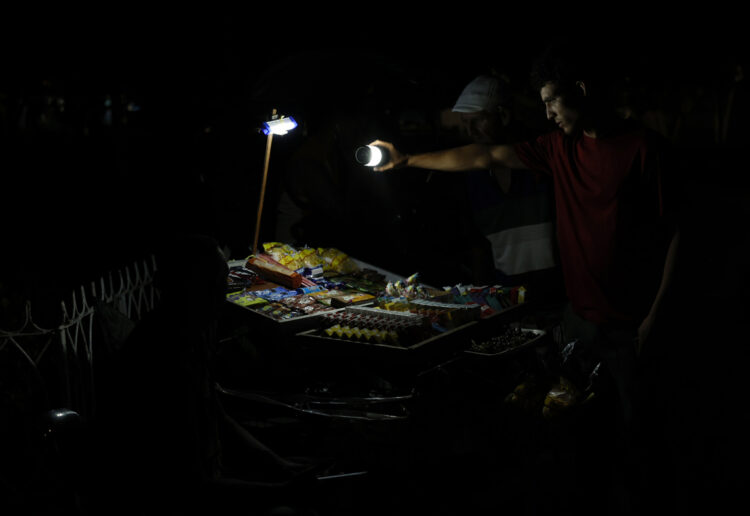 Una persona ilumina con una linterna para ver productos en un puesto callejero en La Habana (Cuba). Foto: EFE/ Ernesto Mastrascusa.