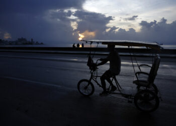 Un bicitaxi transita por el Malecón habanero durante un apagón en La Habana. Foto: Ernesto Mastrascusa / EFE.