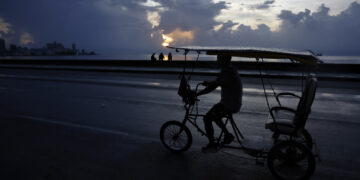 Un bicitaxi transita por el Malecón habanero durante un apagón en La Habana. Foto: Ernesto Mastrascusa / EFE.
