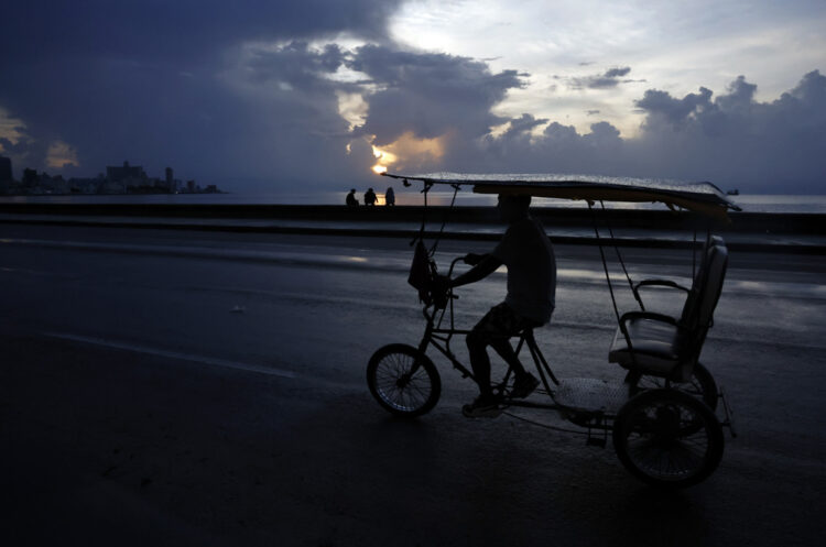 Un bicitaxi transita por el Malecón habanero durante un apagón en La Habana. Foto: Ernesto Mastrascusa / EFE.