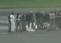 Captura de un video donde se aprecia a los cinco deportados sentados en la losa del aeropuerto, en Liberia, escoltados por personal de seguridad.