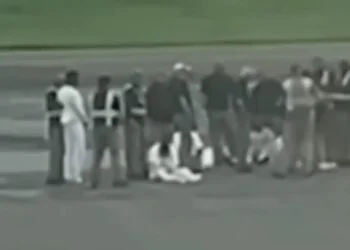 Captura de un video donde se aprecia a los cinco deportados sentados en la losa del aeropuerto, en Liberia, escoltados por personal de seguridad.