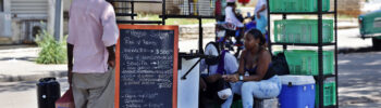Un hombre mira la pizarra de precios de un puesto de comida en una calle en La Habana. Foto: Ernesto Mastrascusa / EFE.
