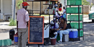 Un hombre mira la pizarra de precios de un puesto de comida en una calle en La Habana. Foto: Ernesto Mastrascusa / EFE.