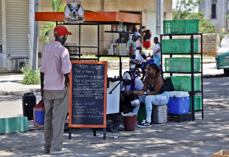 Un hombre mira la pizarra de precios de un puesto de comida en una calle en La Habana. Foto: Ernesto Mastrascusa / EFE.
