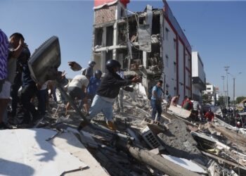 Cali, Colombia (10/08/2026) Personas caminan sobre los escombros de un edificio colapsado este lunes tras el terremoto. Foto: EFE/Ernesto Guzmán.