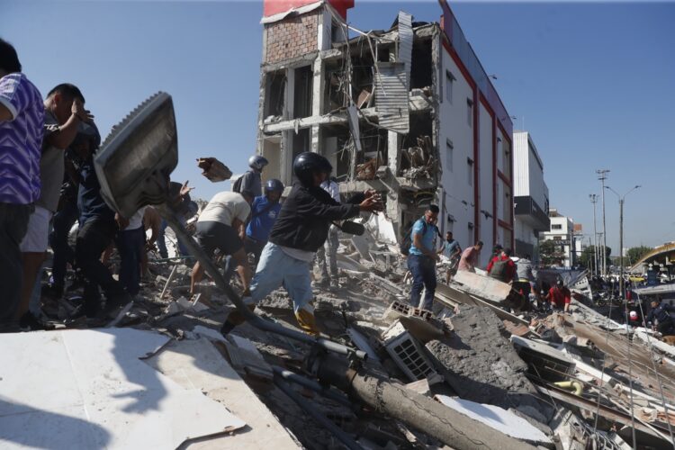 Cali, Colombia (10/08/2026) Personas caminan sobre los escombros de un edificio colapsado este lunes tras el terremoto. Foto: EFE/Ernesto Guzmán.