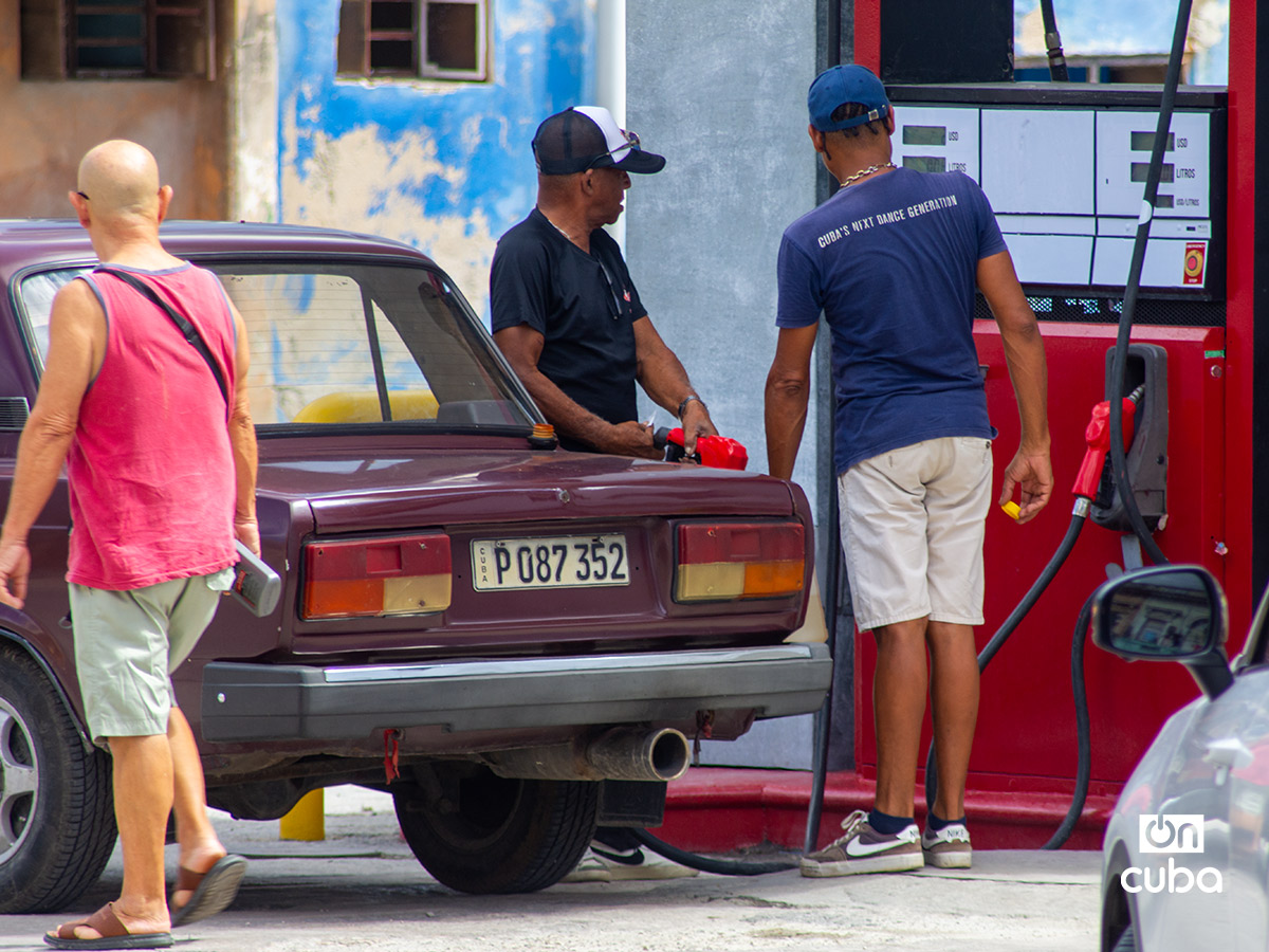 Dos hombres echan gasolina en un auto, en una gasolinera en La Habana. Foto: Otmaro Rodríguez.