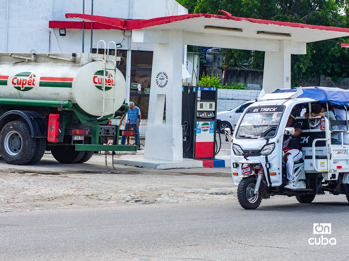 Un triciclo eléctrico pasa cerca de un camión de combustible en La Habana. Foto: Otmaro Rodríguez.
