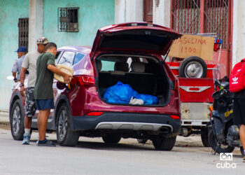 Dos hombres echan gasolina en un auto, junto a un punto de venta informal, en La Habana. Foto: Otmaro Rodríguez.