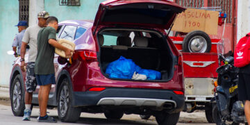 Dos hombres echan gasolina en un auto, junto a un punto de venta informal, en La Habana. Foto: Otmaro Rodríguez.