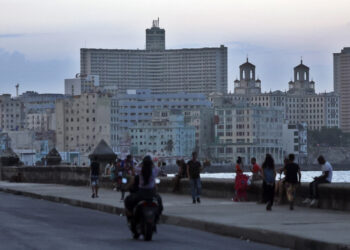 Personas transitan el malecón durante un apagón. Foto: Ernesto Mastrascusa/EFE.