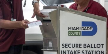 Funcionarios electorales ayudando a los votantes a depositar su boleta de voto por correo en un buzón oficial. Foto: Cristobal Herrera-Ulashkevich/EFE/Epa.