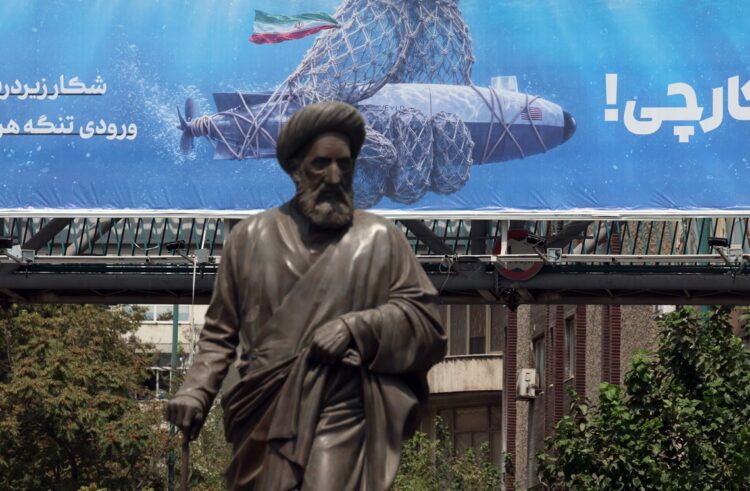 Una estatua se alza frente a una valla publicitaria que muestra un dron submarino estadounidense capturado por el ejército iraní y una frase en persa que dice "Cazando al cazador", en Teherán, Irán, el 9 de septiembre de 2026. Foto: ABEDIN TAHERKENAREH/EFE/EPA.