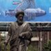 Una estatua se alza frente a una valla publicitaria que muestra un dron submarino estadounidense capturado por el ejército iraní y una frase en persa que dice "Cazando al cazador", en Teherán, Irán, el 9 de septiembre de 2026. Foto: ABEDIN TAHERKENAREH/EFE/EPA.